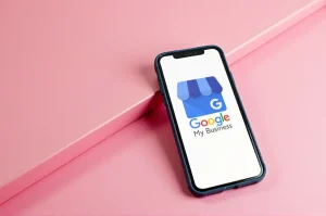 Smartphone displaying the Google My Business app on a pink background, representing the integration of Google My Business with website development services
